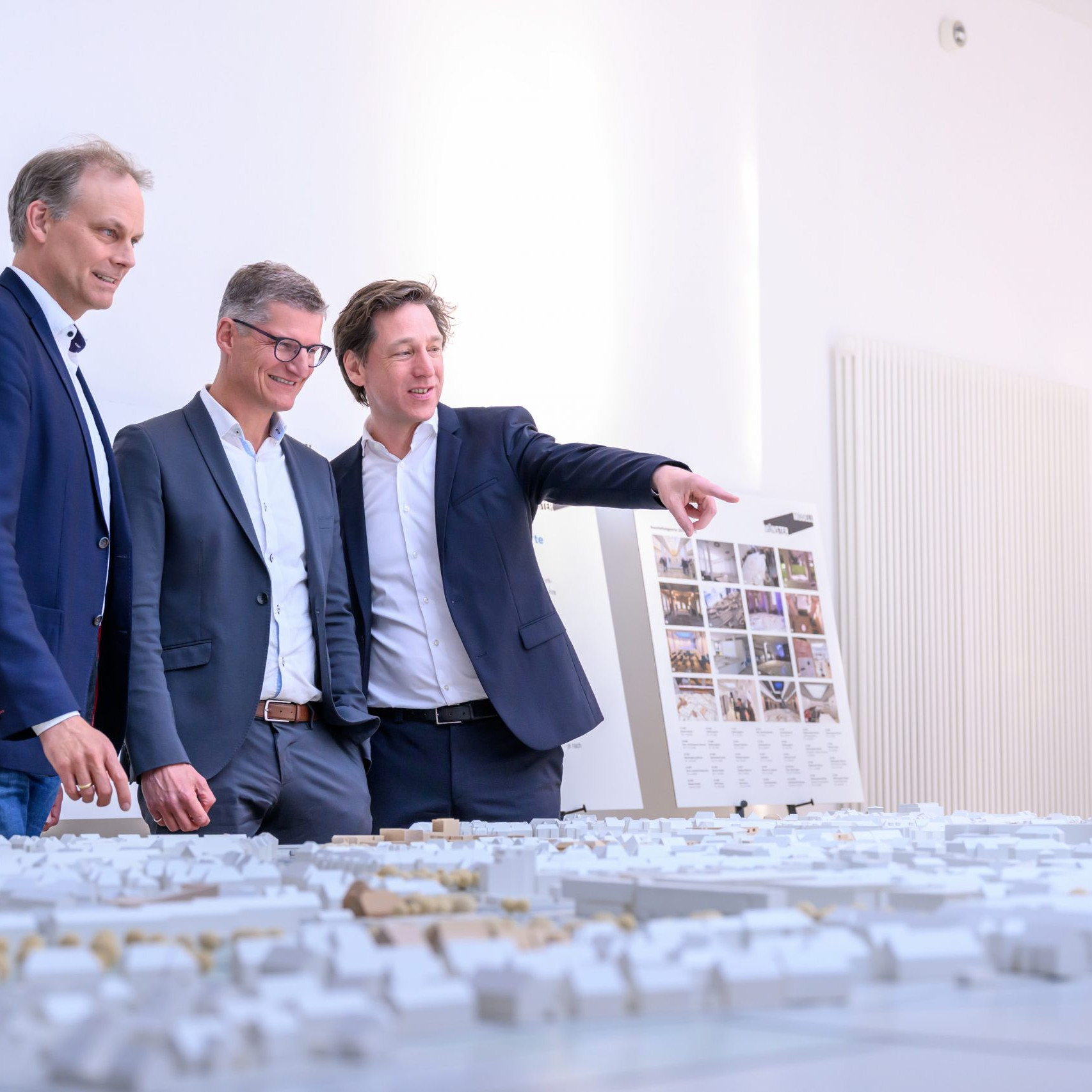 Oberbürgermeister Tilman Fuchs (M.) ließ sich bei der Eröffnung der Ausstellung „Münster Modell – 20 Jahre Forum für Baukultur“ das Münster-Modell vom Vorsitzenden des Vereins Münster Modell e.V., Stefan Rethfeld (r.), und Christopher Festersen, Leiter des Stadtplanungsamtes und Vorstandsmitglied, zeigen. - Foto: Stadt Münster / Michael Möller