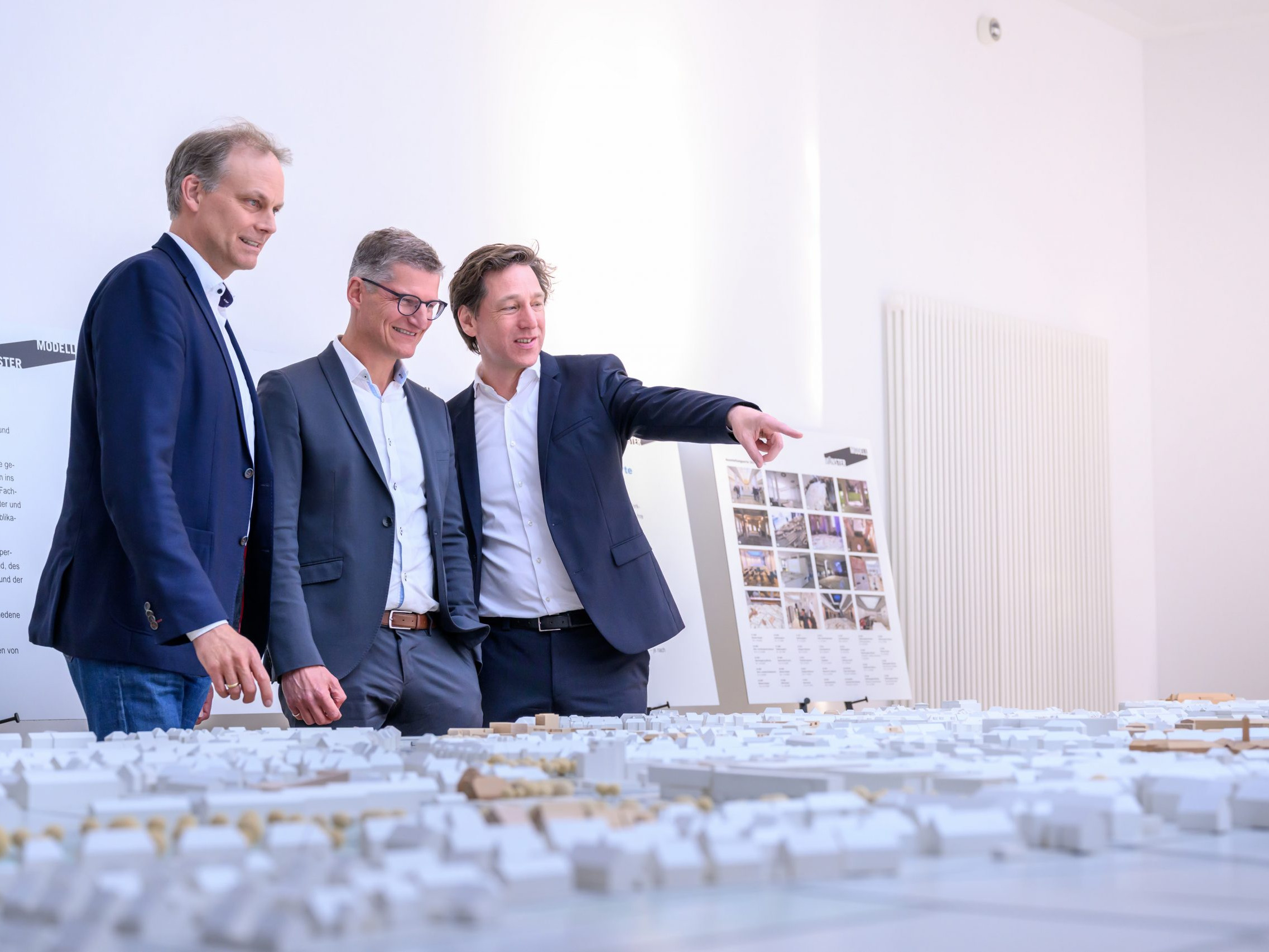 Oberbürgermeister Tilman Fuchs (M.) ließ sich bei der Eröffnung der Ausstellung „Münster Modell – 20 Jahre Forum für Baukultur“ das Münster-Modell vom Vorsitzenden des Vereins Münster Modell e.V., Stefan Rethfeld (r.), und Christopher Festersen, Leiter des Stadtplanungsamtes und Vorstandsmitglied, zeigen. - Foto: Stadt Münster / Michael Möller